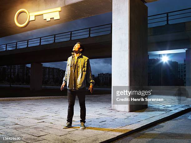 young man in urban environment looking at key - one night stand stock pictures, royalty-free photos & images