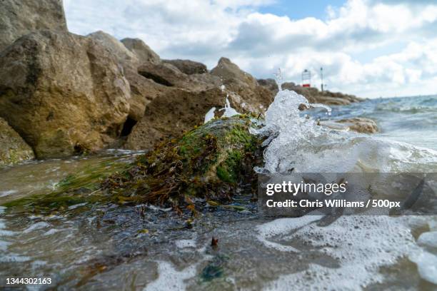 scenic view of rocks by sea against sky,sandbanks,poole,united kingdom,uk - rive photos et images de collection