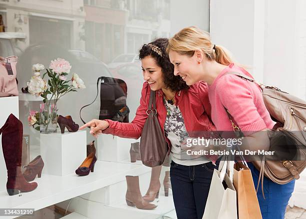 women looking at shoes in shop window. - schoenenwinkel stockfoto's en -beelden