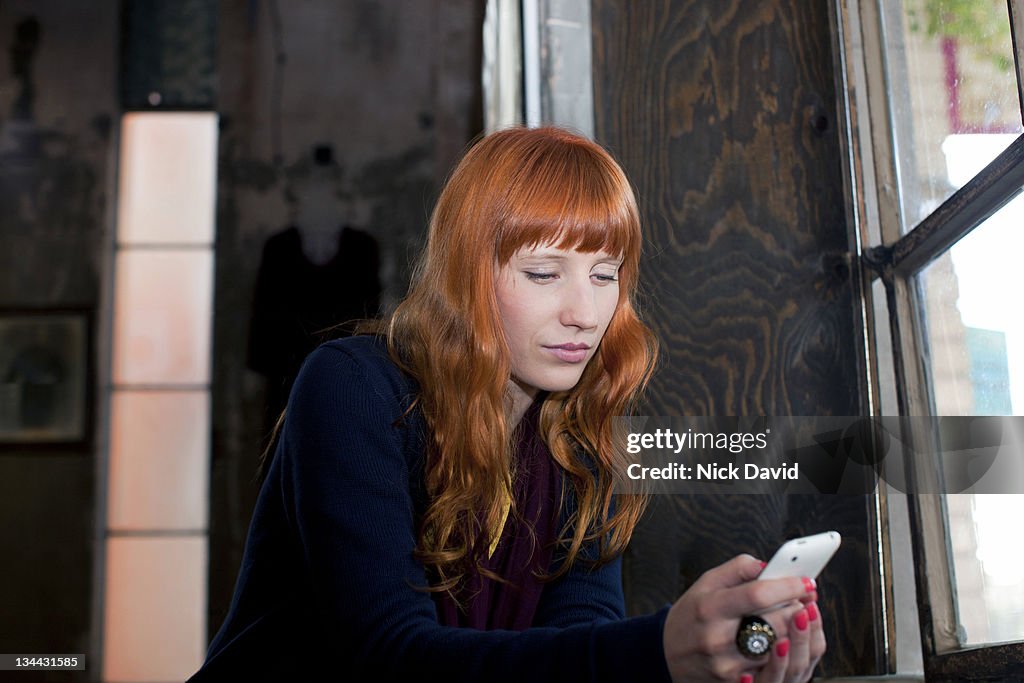 A young women sitting down to look at her smart phone