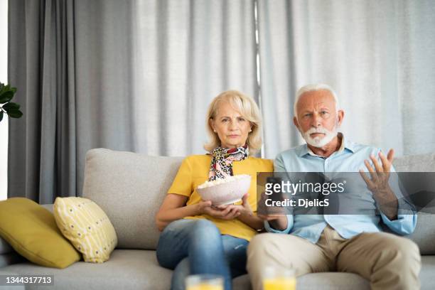 esposo y esposa mayores frustrados viendo la televisión juntos. - lovers 2020 film fotografías e imágenes de stock