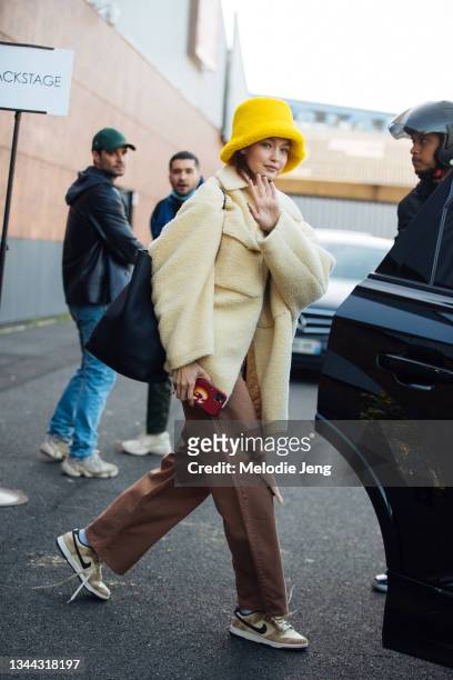 Model Gigi Hadid wears a yellow bucket hat, cream fuzzy jacket, brown pants, and Nike sneakers after the Coperni show on September 30, 2021 in Paris,...