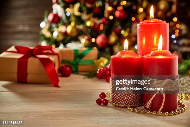 christmas concept: lit red candles with decorated christmas tree on background with copy space - christmas candle foto e immagini stock