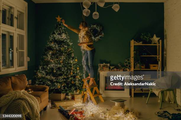 young woman decorating a christmas tree - decorating christmas tree stock pictures, royalty-free photos & images