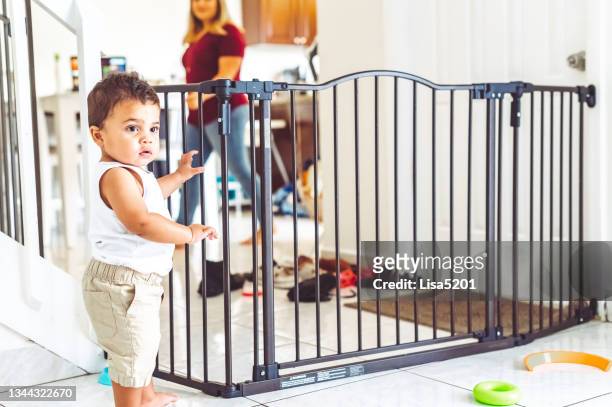 toddler boy trapped in the living room by a baby gate for safety at home - baby gate imagens e fotografias de stock