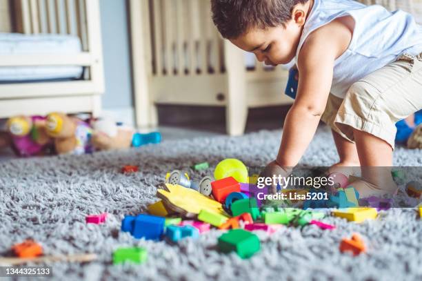 colorido lío de juguetes y el niño pequeño que hizo el lío - kids mess carpet fotografías e imágenes de stock