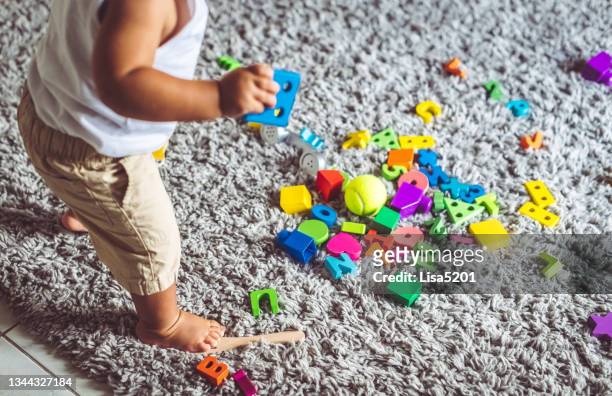 colorido lío de juguetes y el niño pequeño que hizo el lío - kids mess carpet fotografías e imágenes de stock