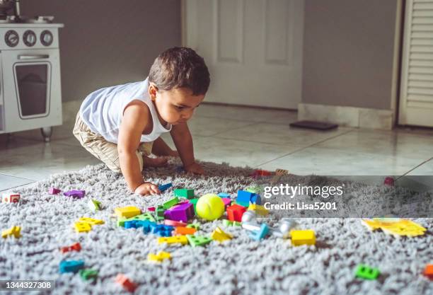 colorido lío de juguetes y el niño pequeño que hizo el lío - kids mess carpet fotografías e imágenes de stock