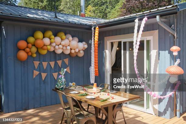a summer outdoor mushroom themed party setup with a colorful balloon arch and birthday flag banner with wrapped present on table. - wolf wallpaper imagens e fotografias de stock