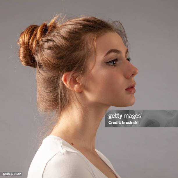 studio portrait of attractive 19 year old woman with brown hair - bun hair woman stock pictures, royalty-free photos & images