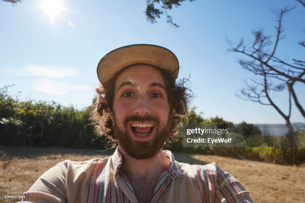POV shot of a man holding a camera taking a selfie making an excited expression.