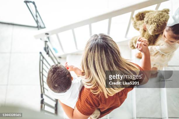 mother helping her young children down the stairs, parenting real people - step sibling stock pictures, royalty-free photos & images