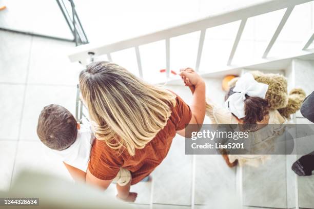 mother helping her young children down the stairs, parenting real people - baby gate stock pictures, royalty-free photos & images