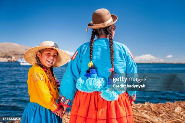 mother and her daughter looking at view on uros floating island, lake tititcaca, peru - puno stockfoto's en -beelden