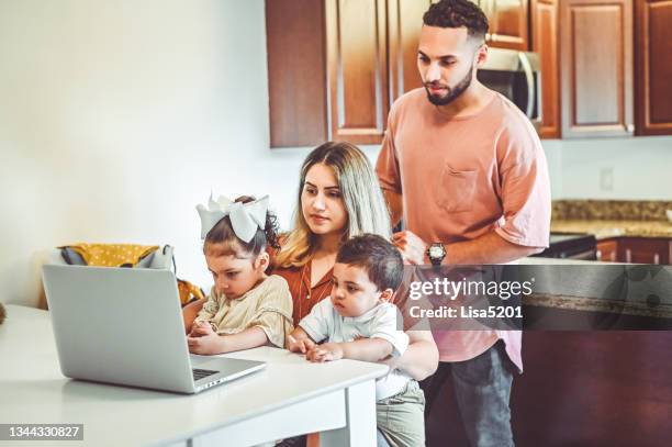 madre y padre junto con dos niños pequeños usan una computadora portátil en un hogar familiar doméstico - típico de clase mediana fotografías e imágenes de stock