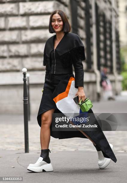 Tiffany Hsu is seen wearing a Loewe dress and green bag with white Loewe shoes outside the Loewe show during Paris Fashion Week S/S 2022 on October...