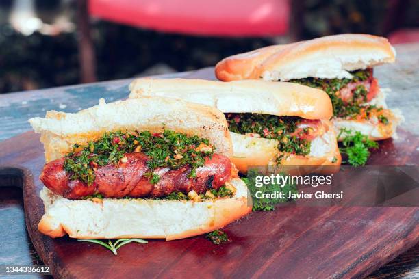 choripán con chimichurri (chorizo a la parrilla, comida tradicional argentina). - chorizo stockfoto's en -beelden