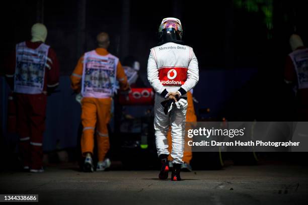 British McLaren Formula One team racing driver Lewis Hamilton wearing his logo adorned fire protection suit overalls walking disconsolately as...