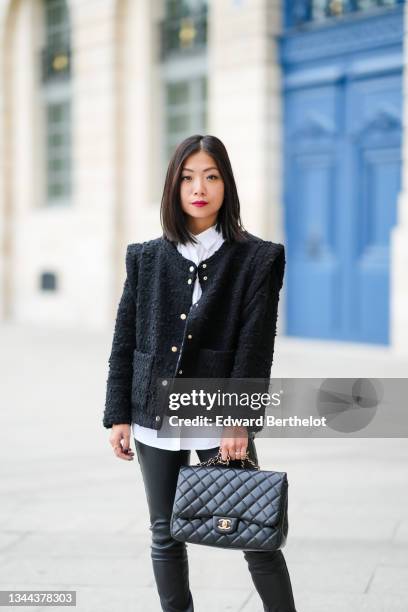 May Berthelot wears a white shirt, a black tweed jacket with epaulets, black shiny leather skinny pants, a black shiny leather Chanel handbag, a...