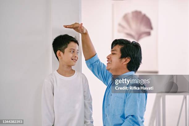 father measuring his son height - malay archipelago stock pictures, royalty-free photos & images