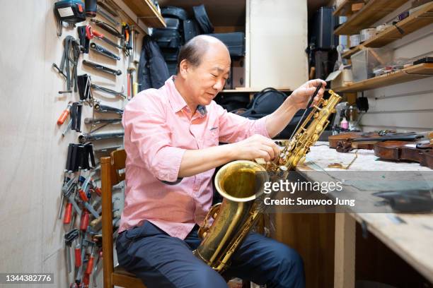 senior man working in musical instrument store - korean ethnicity stock-fotos und bilder