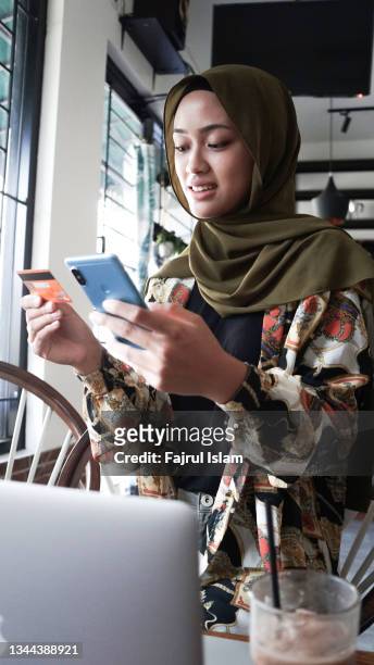 contactless payment of hijab asian women - asian girl doing online shopping ストックフォトと画像