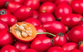 Rose hip half with core hairy seeds in sweet pulp on red fruits texture. Rosa canina