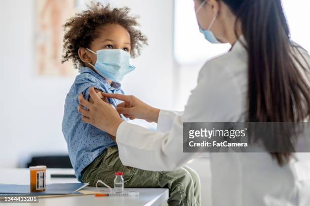 boy receiving a vaccination during a pandemic - child coronavirus sick stock pictures, royalty-free photos & images