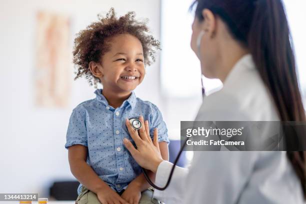 doctor listening to little boys heart - gezondheidszorg en medicijnen stockfoto's en -beelden