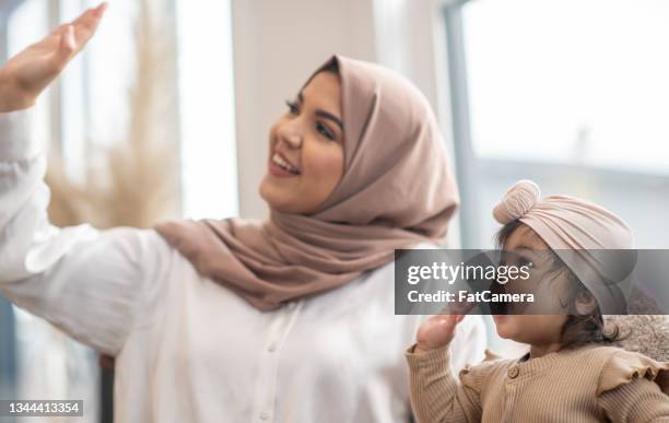 muslim mother and baby waiving goodbye - refugee babies stock pictures, royalty-free photos & images