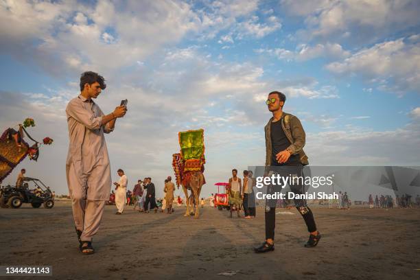 Man walks along the beach as another takes his picture as dusk approaches at Clifton Beach on September 19, 2021 in Karachi, Pakistan. Clifton Beach,...