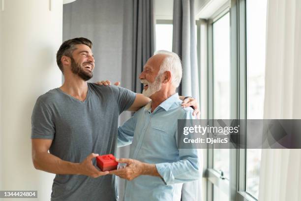 giovane felice che dà un regalo di compleanno a suo padre. - sorpresa regalo foto e immagini stock