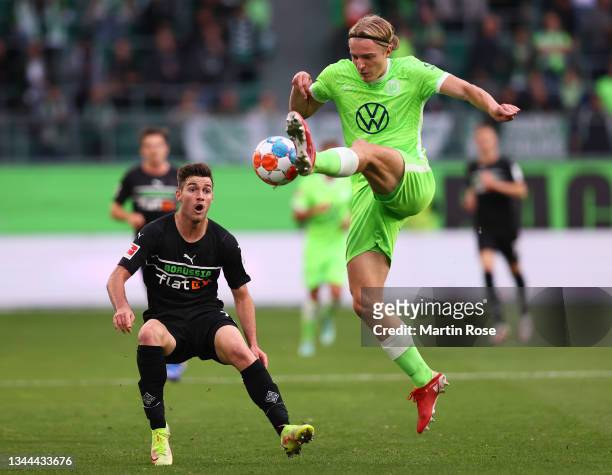 Dodi Lukebakio of Wolfsburg is challenged by Kouadio Kone of Gladbach during the Bundesliga match between VfL Wolfsburg and Borussia Mönchengladbach...