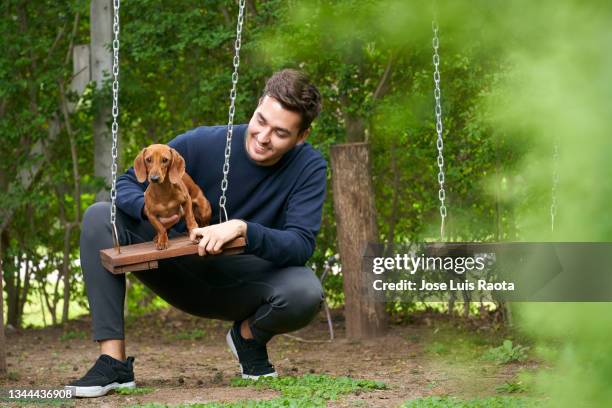 young man plays and has fun with his pet in the park - dachshund holiday stock pictures, royalty-free photos & images