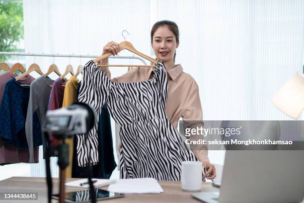 young asia girl selling clothes online by live streaming. selling it online live streaming concept - trade show stockfoto's en -beelden