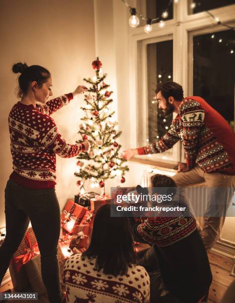 friends exchanging christmas present at home - kerstboom versieren stockfoto's en -beelden