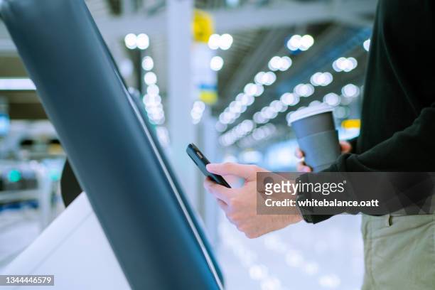 junger asiatischer mann, der mit dem flugzeug reist und am flughafen mit einem automaten selbst eincheckt - selbstbedienung stock-fotos und bilder