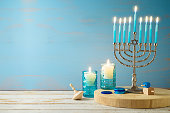 Jewish holiday Hanukkah concept with menorah, candles and dreidel on wooden table. Background for greeting card or banner