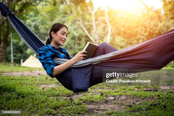 happy camping in a hammock reading a book. - recreational equipment stock pictures, royalty-free photos & images