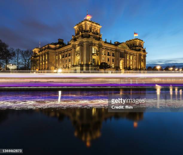 reichstag building and passing boat at blue hour (german parliament building) - berlin, germany - bundestag - fotografias e filmes do acervo