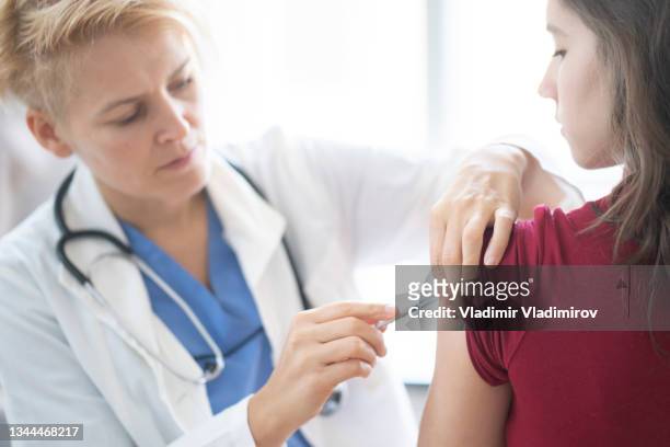 teenage girl getting vaccinated - arm needle stockfoto's en -beelden