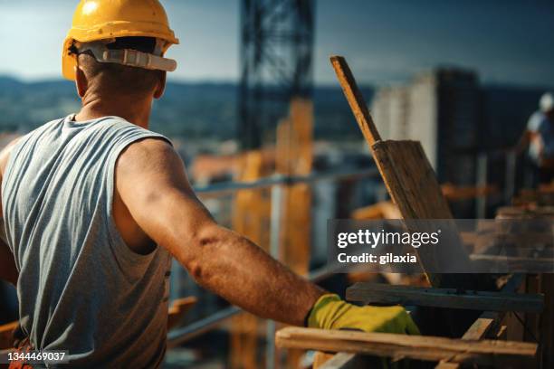 bauarbeiter auf einem gebäude. - construction workers stock-fotos und bilder