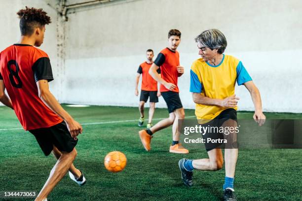 male players practicing at indoor soccer field - een pass geven stockfoto's en -beelden