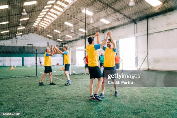 soccer teammates celebrating after winning the match - indoor football pitch stock pictures, royalty-free photos & images