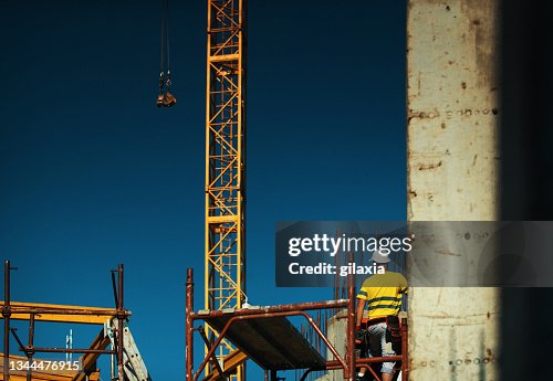 Construction worker loading cargo onto a construction crane Construction worker loading cargo onto a construction crane