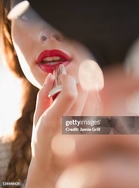 young woman applying red lipstick - lippenstift stock-fotos und bilder