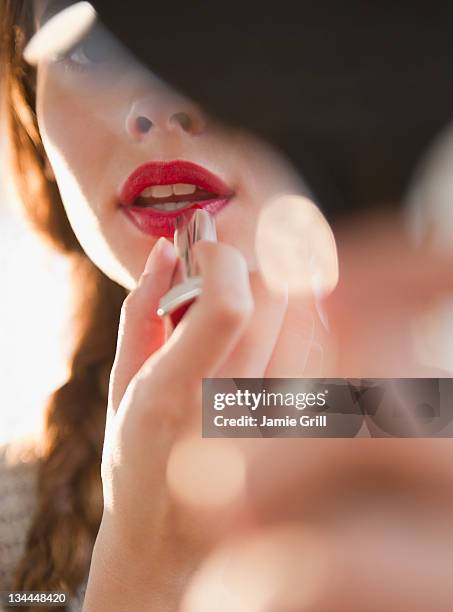young woman applying red lipstick - lipstick imagens e fotografias de stock