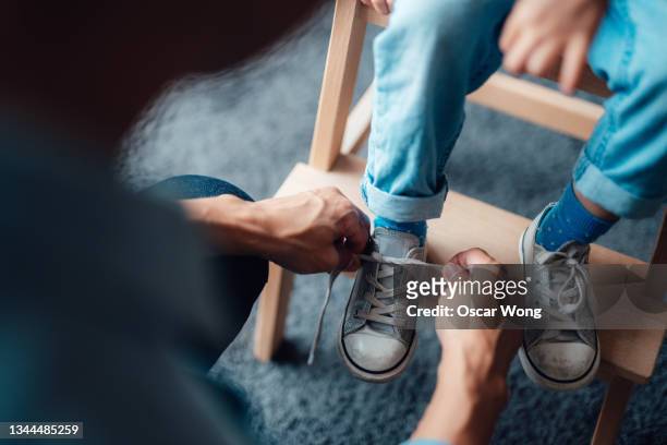 close-up shot of father tying shoelace for his child - blaue schuhe stock-fotos und bilder