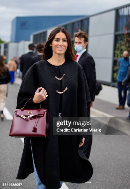 Deborah Reyner Sebag seen waring black cape, bordeaux Hermes bag outside Hermes during Paris Fashion Week - Womenswear Spring Summer 2022 on October...