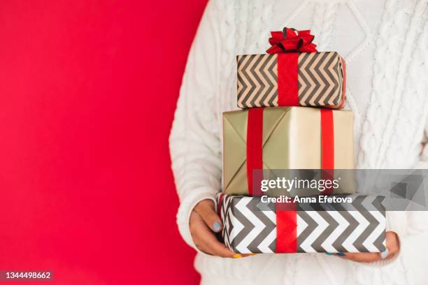 heap of different gift boxes in hands of woman in white sweater. new year celebration concept. front view with copy space - three year stock pictures, royalty-free photos & images